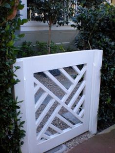 an open white gate in front of some bushes