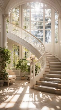 an elegant staircase in the middle of a room with large windows and potted plants