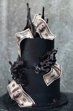 a three tiered cake with money sticking out of it's sides and black icing