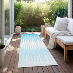 a white and blue rug sitting on top of a wooden floor next to a couch