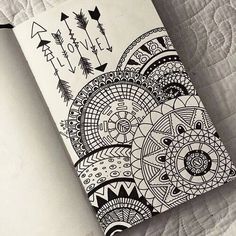 an open notebook with black and white designs on the cover sitting on top of a bed