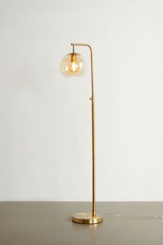 a brass floor lamp with a glass globe shade