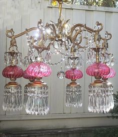 a pink chandelier hanging from the ceiling in front of a white fenced area