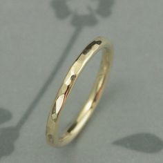 a close up view of a gold wedding ring on a table with shadow from the floor