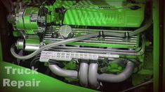 the engine compartment of a green truck with chrome piping on it's side