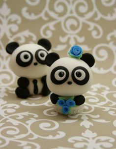 two small panda bears with blue flowers on their heads, one is black and the other is white