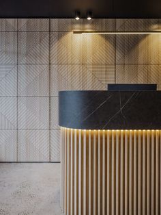 a black and gold reception counter in front of a wall with geometric tiles on it