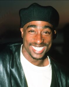 a smiling man wearing a black hat and leather jacket