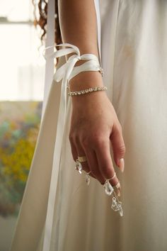 a woman in a white dress holding onto her wedding bracelet