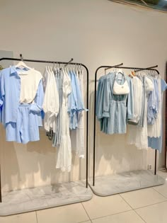 two racks with clothes hanging on them in front of a mirror and tiled flooring