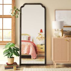 a large mirror in the corner of a room next to a dresser and bed with a potted plant on it