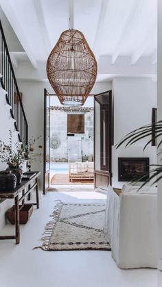 a living room filled with furniture and a hanging light over the fire place in front of an open door