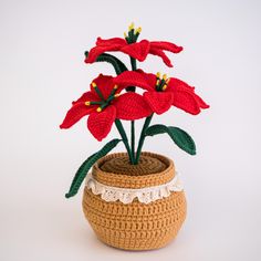 a crocheted vase with red flowers in it on a white background, the bottom half has green leaves