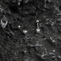 two pairs of silver earrings sitting on top of a rocky surface in black and white