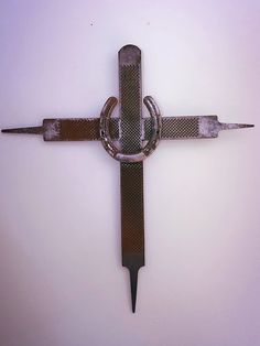 a cross made out of metal with chains attached to the side and two knives stuck in it