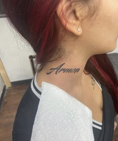 a woman with red hair has a name tattoo on her neck and behind her ear