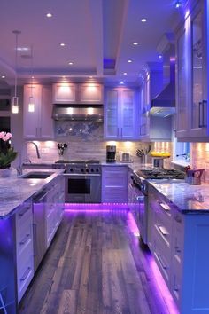 a kitchen with white cabinets and purple lights on the counter tops, along with an island in the middle