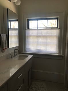 a bathroom with a sink, mirror and two lights on the side of the window