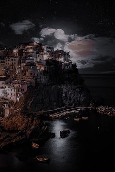 the night sky is full of stars and clouds over a village on a cliff overlooking the ocean