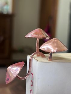 two pink metal mushrooms sitting on top of a white box