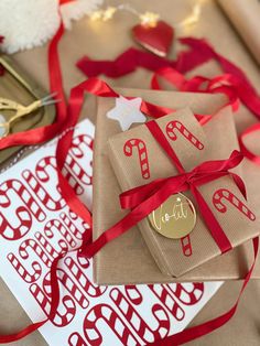 presents wrapped in brown paper with red ribbon and gold foil stamping are on the table