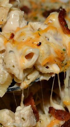 a spoon full of pasta with bacon and cheese on it is being lifted from the casserole dish