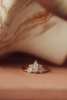 three stone diamond ring sitting on top of a pink marble surface next to a pillow