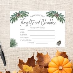 a place card with autumn leaves and pine cones on it, next to a pen