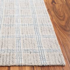 a white rug with blue and gray squares on top of wooden floor next to hardwood floors