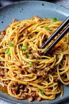 a plate with noodles and chopsticks on it