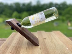 a wine bottle on a wooden stand with a green field in the backgroud