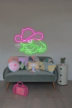 a couch with pillows and a neon sign on the wall