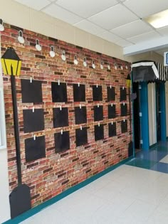 a brick wall with several pieces of black paper pinned to it and hanging from the ceiling