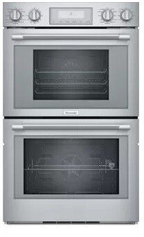 two silver ovens side by side on a white background