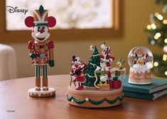 two christmas figurines sitting on top of a table next to a snow globe