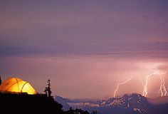 a tent pitched in the mountains under a lightning storm