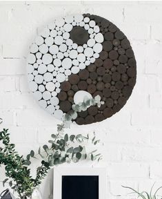 a white and black yin - yang sign on a wall next to a potted plant