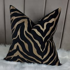 a black and gold zebra print pillow sitting on top of a white fur covered bed