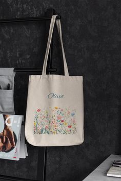 ABOUT OUR Floral Name Tote Bag. This 100% cotton bag comes in one size - 15" x 16"- perfect for everyday wear. While the canvas material will show off your designs in great colors, it's durable and will last for years. The bag features 20" handles (made from the same canvas), making it easy to carry even with a week's worth of shopping. - 100% cotton canvas - Heavy fabric (12 oz/yd² (406.9 g/m - Sewn-in label - Available in natural and black colors Thank you for trusting us! Personalized Multicolor Bags As Gifts, Multicolor Personalized Bags For Gift, Personalized Multicolor Bags, Floral Shaped Cotton Gift Bag, Mother's Day Gift Floral Print Bag, Mother's Day Floral Print Gift Bag, Rectangular Canvas Bag With Floral Print For Gifts, Rectangular Canvas Bag With Floral Print As Gift, Personalized Cotton Bags For Daily Use