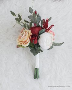 a bridal bouquet on a white furnishing with red, orange and pink flowers