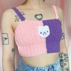 a woman with tattoos wearing a pink and purple crop top