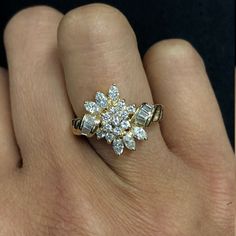 a person's hand with a gold and white diamond ring on top of it