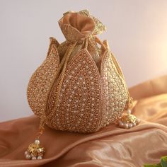 Discover the Elegant Lotus Potli Bag by THE TAN CLAN Elevate Your Style with Our Unique Embroidered Indian Bridal Potli Bag by THE TAN CLAN Transform your accessory collection with the Elegant Lotus Potli Bag--a stunning fusion of traditional craftsmanship and modern design. This exquisite embroidered potli bag is perfect for weddings, engagements, bridesmaid gifts and anniversary gifts. With its intricate detailing and luxurious finish, this bag is a must-have for anyone looking to add a touch Gold Potli Bag With Dori Work For Reception, Festive Gold Potli Bag For Reception, Gold Potli Bag For Diwali Reception, Gold Potli Bag With Handwork For Reception, Traditional Gold Potli Bag For Reception, Traditional Bags With Gold Embroidery For Reception, Gold Handwork Potli Bag For Reception, Gold Embroidered Bag For Reception, Gold Bag With Gold Embroidery For Reception