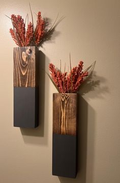 two wooden vases with dried flowers in them on the wall next to each other