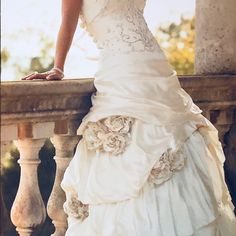 a woman in a wedding dress standing on a balcony with her hand on the railing