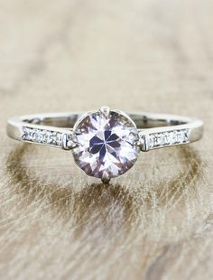 a white gold engagement ring with a pink diamond center stone and pave set diamonds around the band