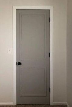 an empty room with a gray door and white walls