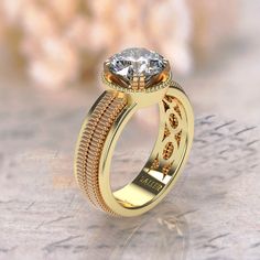 a yellow gold ring with a diamond on the top and an intricate band around it