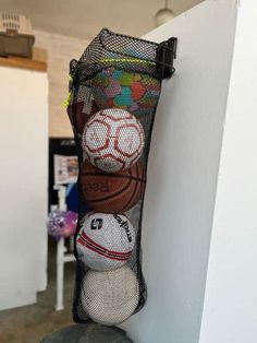 several balls are in a mesh bag hanging on the wall