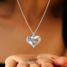 a woman holding a heart shaped pendant with words on the front and back of it